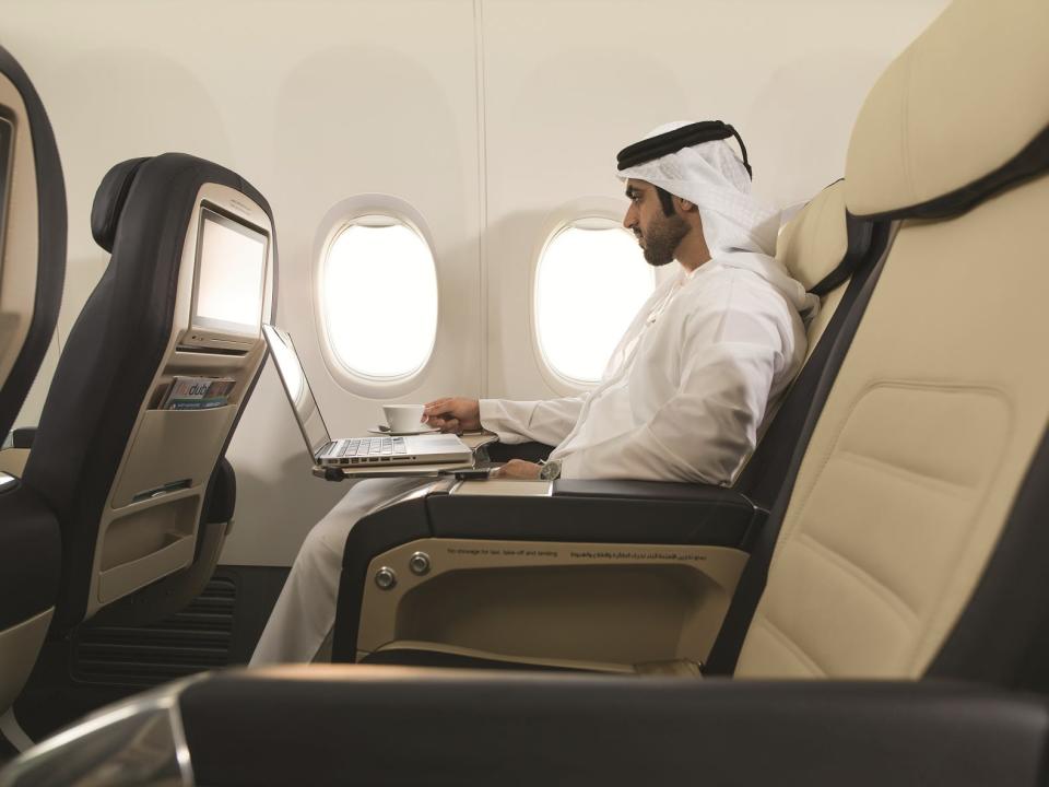 Flydubai's original business class recliner seat with a man sitting in the seat working on a laptop.