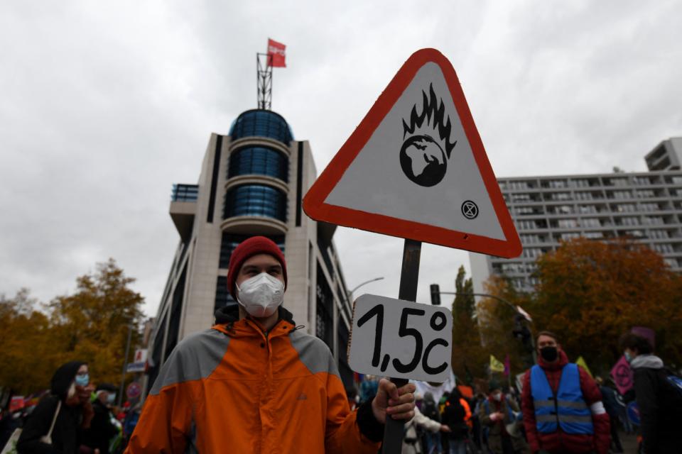 An activist holds up a placard showing a burning planet Earth and making reference to the 2015 Paris Agreement to limit global warming preferably to 1,5 degrees Celsius, during a climate strike demonstration of Fridays for Future in front of the Willy Brandt Haus, headquarters of Germany's Social Democratic Party SPD, in Berlin on October 22, 2021. (Photo by INA FASSBENDER / AFP) (Photo by INA FASSBENDER/AFP via Getty Images)