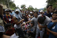 Honduran migrants receive free water from Guatemalan police at the Honduran border crossing that connects with Agua Caliente, Guatemala, Monday, Oct. 15, 2018. Hundreds of Honduran migrants were eventually allowed to cross at the Guatemalan border under a broiling sun Monday hoping to make it to new lives in the United States, far from the poverty and violence of their home nation. (AP Photo/Moises Castillo)