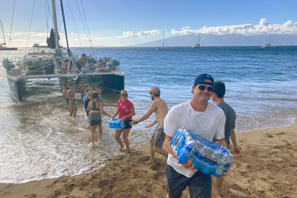 2023年8月12日，夏威夷茂宜島居民在卡納帕利海灘（Kaanapali Beach）接力運送物資上岸。美聯社