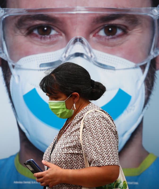 A woman wearing a protective face mask walks past a dental clinic advertisement at Vallecas neighbourhood in Madrid