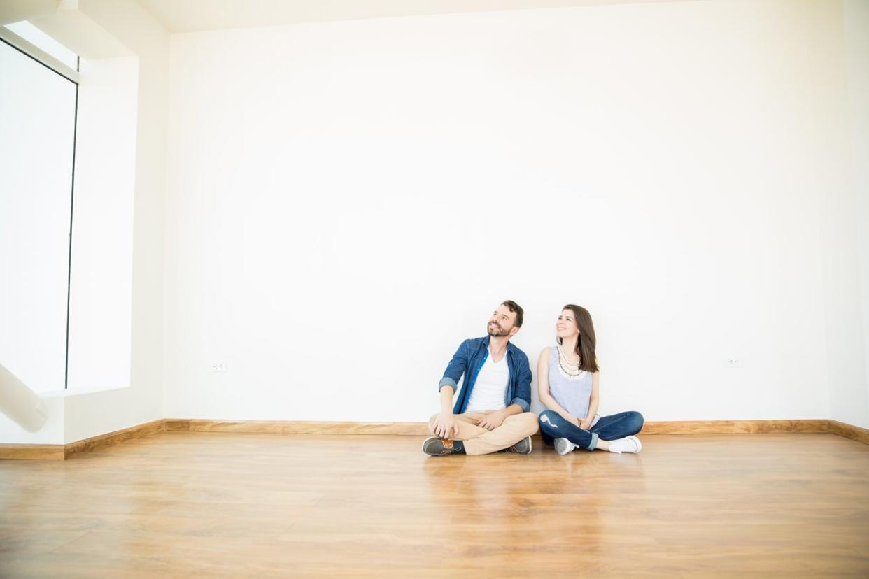 Owners Looking Away While Sitting On Floor In New Home