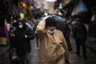 A man carries goods on his shoulder in a street market in Istanbul, Turkey, Wednesday, Jan. 12, 2022. Turkey's government and central bank have taken a series of complex steps in recent weeks to prop up a beleaguered economy crippled by skyrocketing consumer prices, instead of ending a much-criticized plan to cut interest rates. (AP Photo/Francisco Seco)