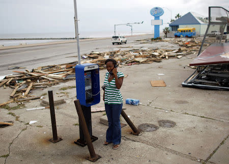 A resident talks on a public phone next to debris left by Hurricane Ike in Galveston, Texas September 14, 2008. REUTERS/Carlos Barria