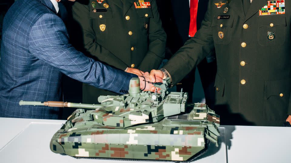 Fair attendees pictured in front of a battle tank model at the SITDEF fair in Lima, Peru in 2019. - Nikita Teryoshin