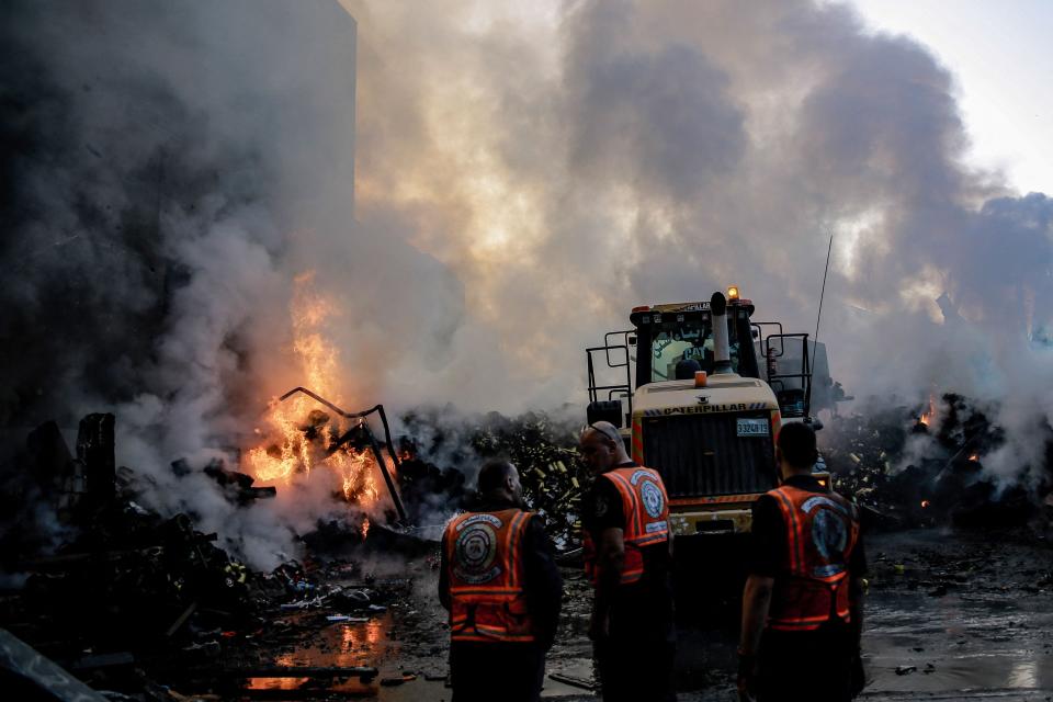 Smoke and fire rise from buildings as rescuers gather following Israeli airstrikes on Gaza (AFP via Getty Images)