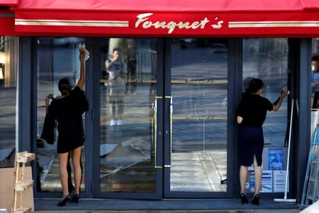 Employees clean up the windows of the Fouquet's restaurant on the eve of its reopening on the Champs Elysees, almost 4 months after it was ranksacked by a "yellow vests" protest in Paris