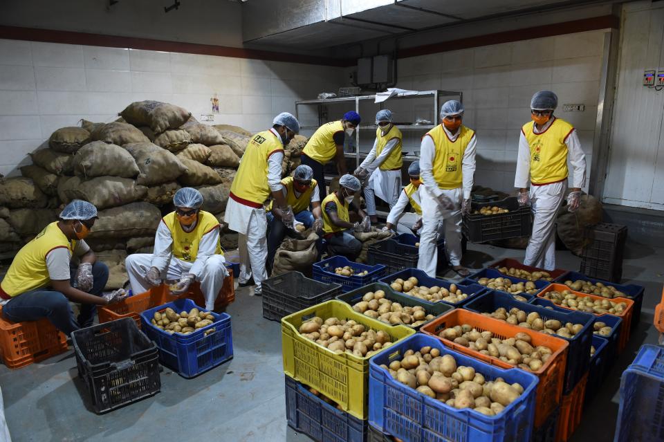 Volunteers of the Bochasanwasi Akshar Purushottam Sanstha (BAPS) prepare vegetables for distributing among poor residents during a government-imposed nationwide lockdown as a precautionary measure against the COVID-19 novel coronavirus in Ahmedabad on March 28, 2020. (Photo by Sam PANTHAKY / AFP) (Photo by SAM PANTHAKY/AFP via Getty Images)