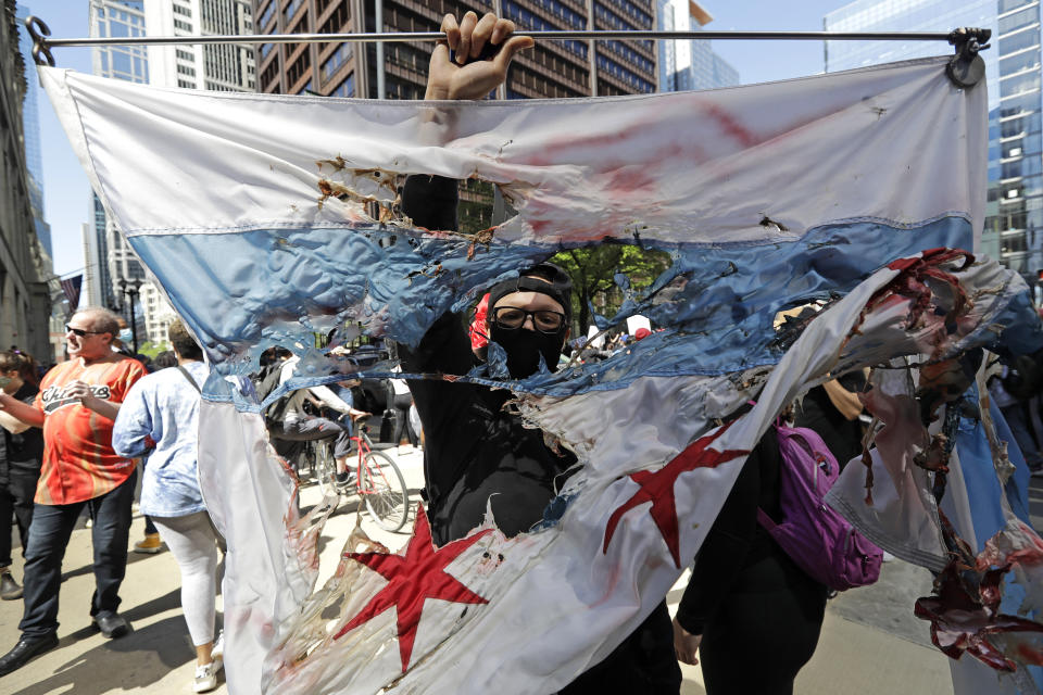 A protester holds a burned Chicago flag during a protest over the death of George Floyd in Chicago, Saturday, May 30, 2020. Protests across the country have escalated over the death of George Floyd who died after being restrained by Minneapolis police officers on Memorial Day, May 25.. (AP Photo/Nam Y. Huh)