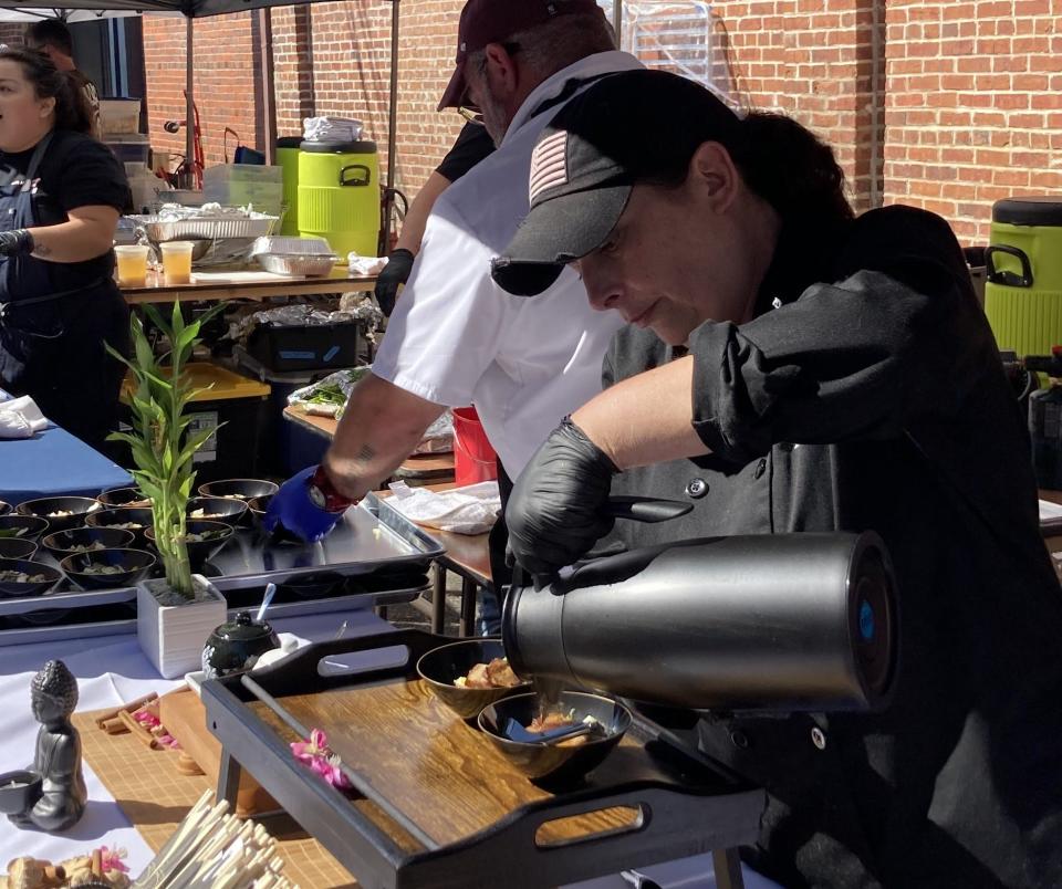 Chef Penny Hayes prepares samples of smoky Japanese noodles with crispy pork belly at the Town Square Cook-off, where 12 chefs advance in chance to win their own Burgaw restaurant.