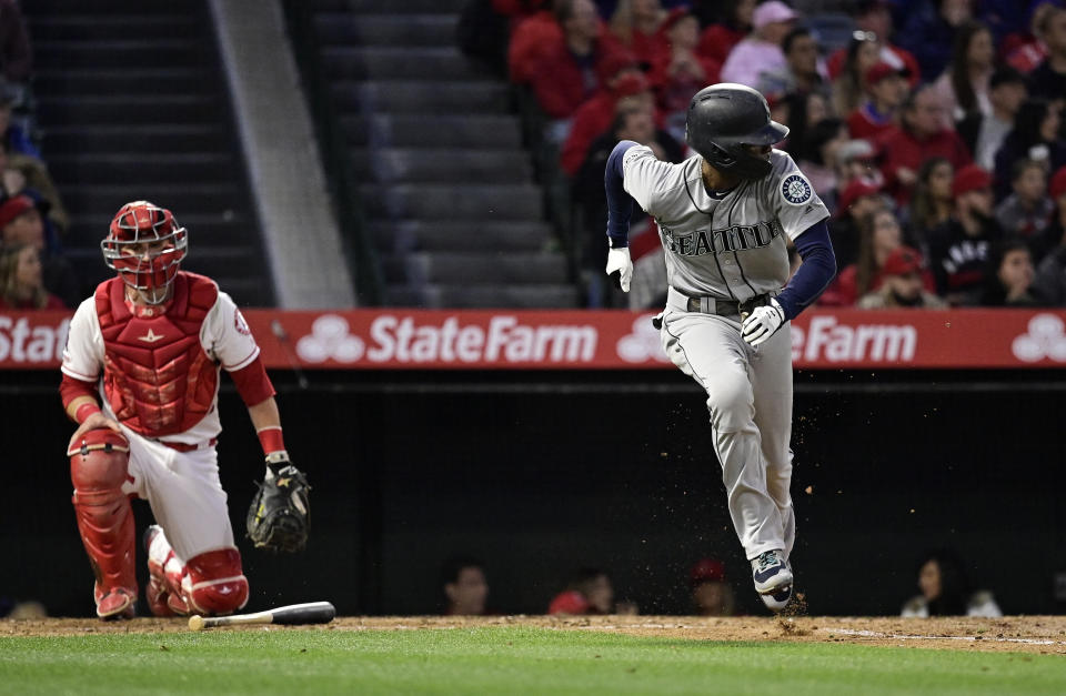 Seattle Mariners' Dee Gordon, right, runs to first as he hits an RBI single while Los Angeles Angels catcher Jonathan Lucroy watches during the fourth inning of a baseball game Saturday, April 20, 2019, in Anaheim, Calif. (AP Photo/Mark J. Terrill)