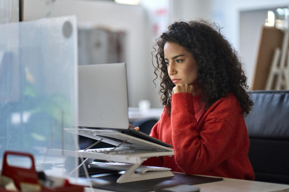 a woman looking at her laptop sitting at a desk