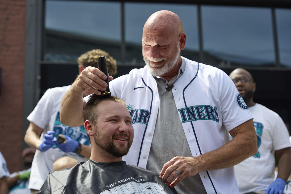 Seattle Mariners catcher Cal Raleigh has his head shaved by former Mariners player Jay Buhner on Buhner Buzz Night, Thursday, June 13, 2024, in Seattle. The promotion is based on Buhner's shaved-head style. (AP Photo/John Froschauer)