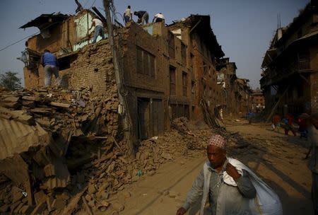A man carrying goods walks past collapsed houses after the April 25 earthquake at Bhaktapur May 7, 2015. REUTERS/Navesh Chitrakar