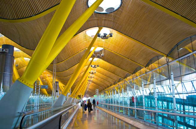 <p><strong>Where: </strong>Madrid, Spain</p> <p>The design of in the Madrid-Barajas Airport has been described as joyful and exuberant. We’d like to throw in whimsical and inspiring too. The undulating wooden ceiling is supported by a canopy of rainbow colored trees that makes it seem like you’re walking through a magical forest. Other notable design elements include the massive, disk-shaped lights and air conditioning vents, which look like sculptures. The architects, the Richard Rogers Partnership (as it was then called), won the prestigious Stirling Design in 2006 for their work on Terminal 4.</p> <p><strong>Plan Your Trip: </strong>Visit </p>