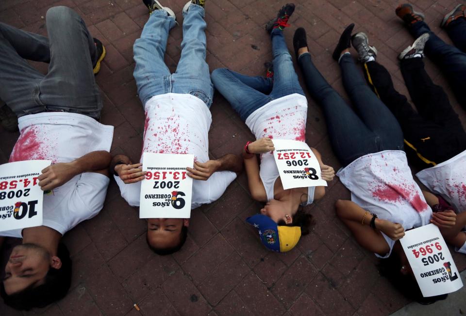 Demonstrators lie on the ground holding statistics about the people murdered in the 14 years of Chavista government, at a protest in Caracas, Venezuela, Friday, March 7, 2014. Venezuela is coming under increasing international scrutiny amid violence that most recently killed a National Guardsman and a civilian. United Nations human rights experts demanded answers Thursday from Venezuela's government about the use of violence and imprisonment in a crackdown on widespread demonstrations. (AP Photo/Fernando Llano)