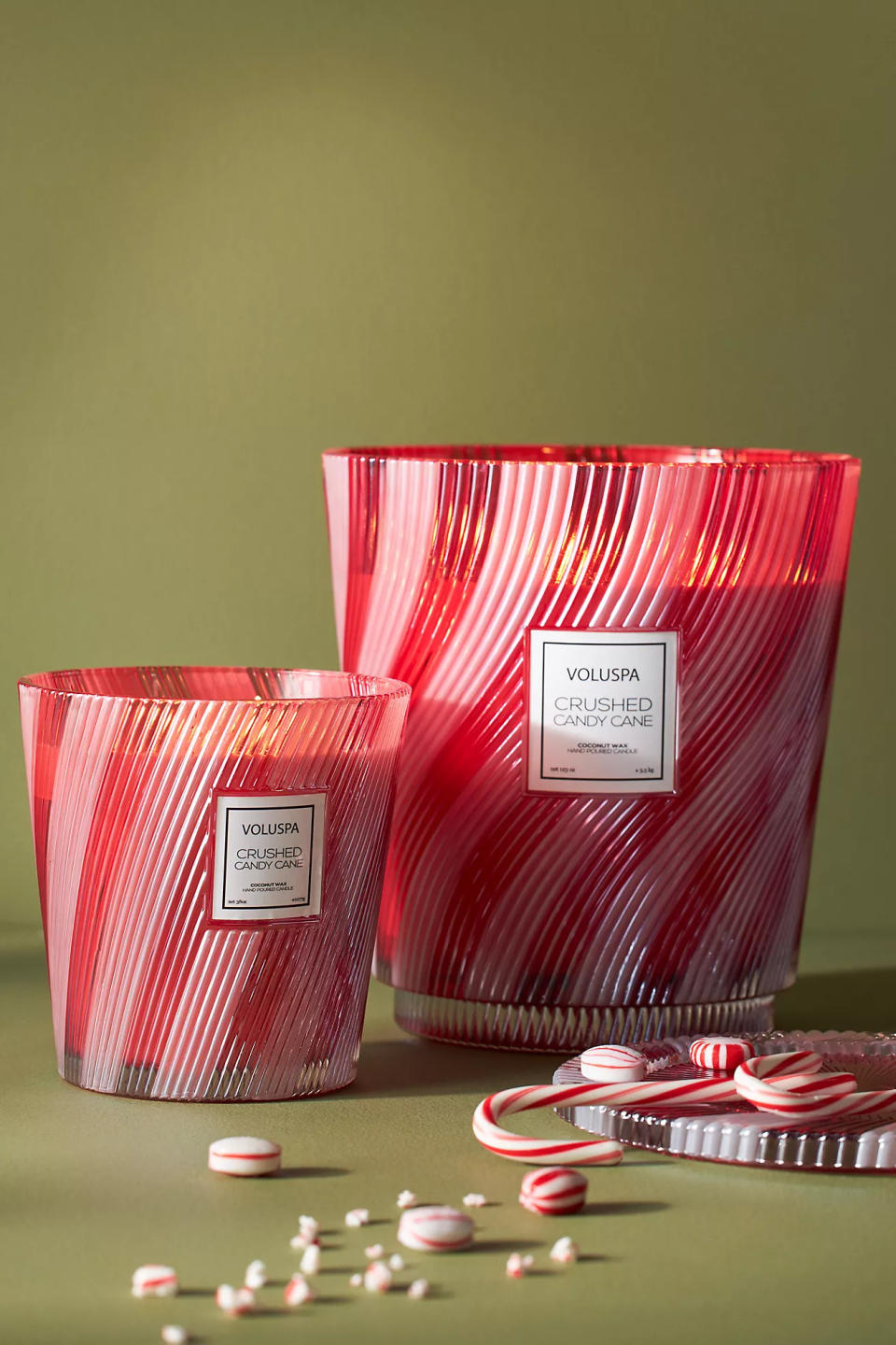 two of the candy cane candles beside candy canes and candy