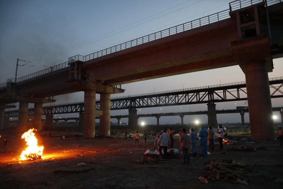 Relatives stand near the funeral pyre of their loved one who died due to COVID-19 at a cremation ground in Prayagraj, India, Saturday, May 8, 2021. (AP Photo/Rajesh Kumar Singh)