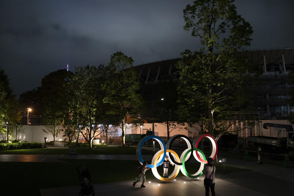 Two children pose for photos with the Olympic Rings in front of New National Stadium in Tokyo, June 23, 2019. (AP Photo/Jae C. Hong)