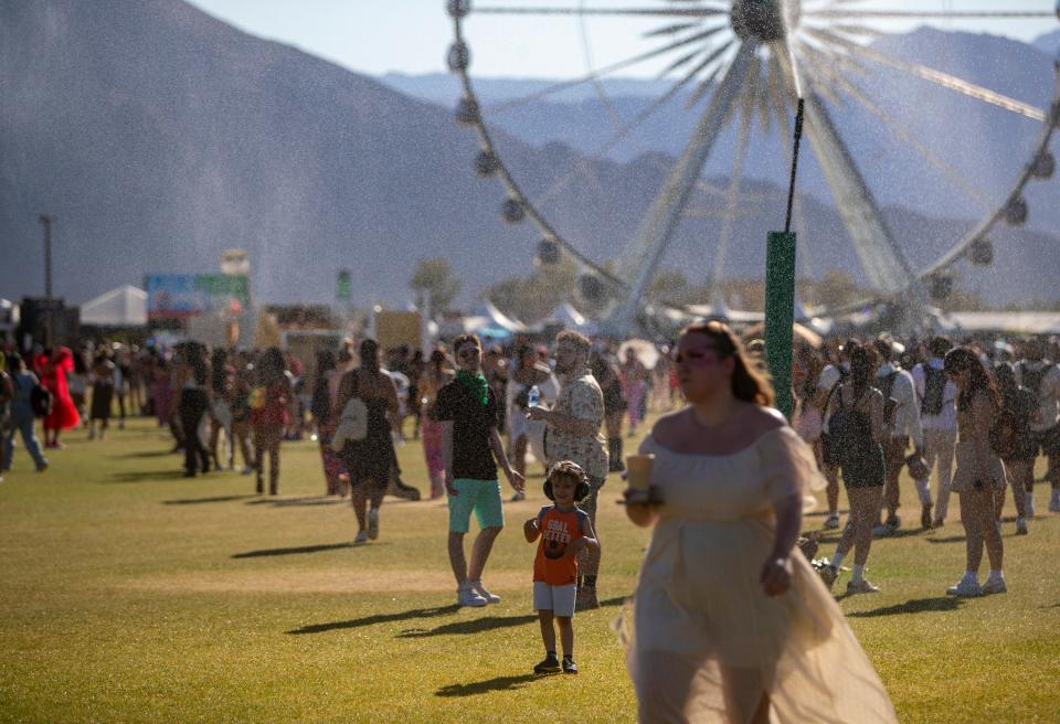 Festivalgoers walk through the sprinklers to keep cool during the Coachella Valley Music and Arts Festival in Indio, Calif., Sunday, April 21, 2024.