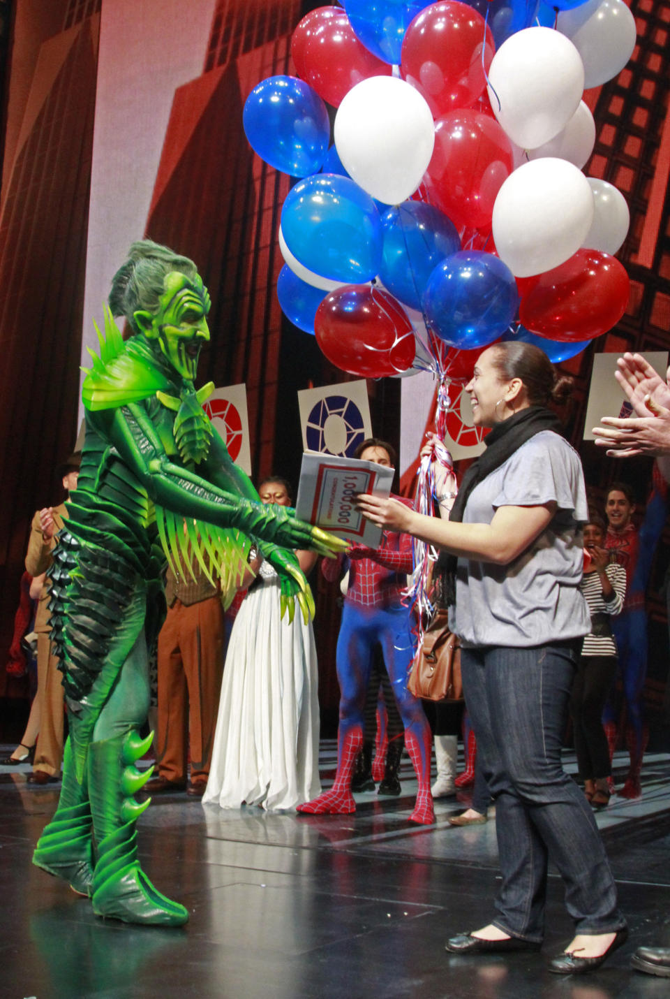 "Spider-Man Turn of the Dark" star Patrick Page, left, who plays the Green Goblin, gives an award to Yvelisse Fermin, from the New York City borough of Queens, for being the one millionth viewer of the production on Wednesday, May 16, 2012, in New York. (AP Photo/Bebeto Matthews)