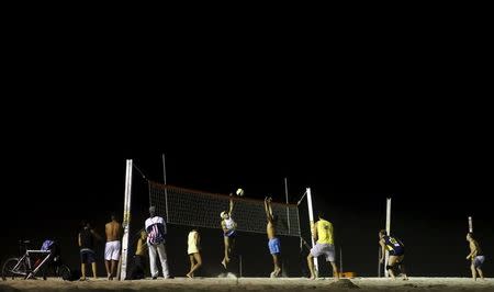 Residents play beach volleyball during at night on Copacabana beach, where the Olympic beach volleyball will take place in Rio de Janeiro, Brazil, July 9, 2015. REUTERS/Sergio Moraes