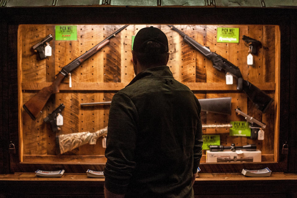 A man looks at a gun display on the first day of the NRA's annual meeting in Dallas.