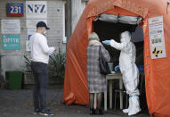 People arrive to be tested for COVID-19 in Warsaw, Poland, Thursday, Oct.22, 2020. With cases surging in central Europe, some countries are calling in soldiers, firefighters, students and retired doctors to help shore up buckling health care systems. Many faced a shortage of medical personnel even before the pandemic, and now the virus has sickened many health workers, compounding the shortfall. (AP Photo/Czarek Sokolowski)