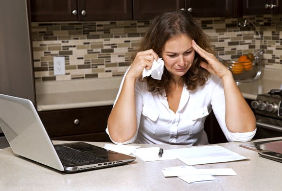 Woman crying while looking at paperwork on top of her kitchen table