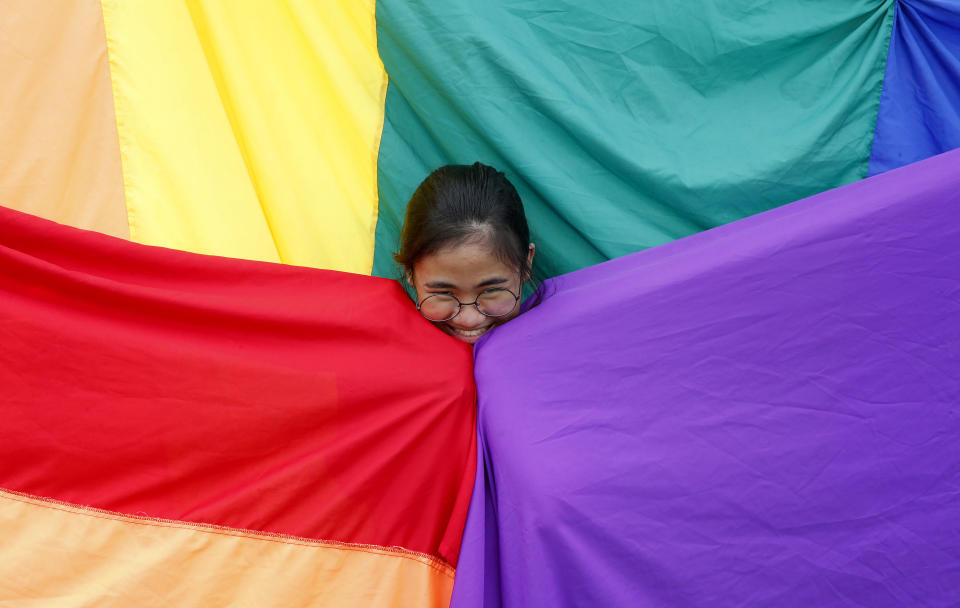 FILE - A supporter of the Philippine LGBT (Lesbians Gays Bisexual Transgender) group poses before the rainbow flag during the annual celebration of "Pride March" June 30, 2018, in Marikina city, east of Manila, Philippines. Singapore’s announcement Sunday, Aug. 22, 2022, that it would decriminalize sex between men is being hailed as a step in the right direction for LGBTQ rights in the Asia-Pacific region, a vast area of nearly 5 billion people with different laws and attitudes. (AP Photo/Bullit Marquez, File)