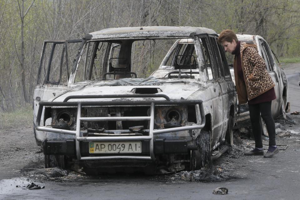 A local resident inspects burnt-out cars after night fight at the checkpoint which under control of pro-Russian activists in the village of Bulbasika near Slovyansk on Sunday, April 20, 2014. Pro-Russian insurgents defiantly refused to surrender their weapons or give up government buildings in eastern Ukraine, despite a diplomatic accord reached in Geneva and overtures from the government in Kiev. (AP Photo/Efrem Lukatsky)