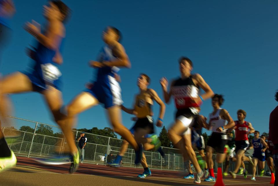 Runners compete in the boys 1600 meters at the Sac-Joaquin Section Division I track and field finals at Elk grove High School. On May 17, 2013. A slow shutter speed causes the runners to be blurred and gives a sense of motion.