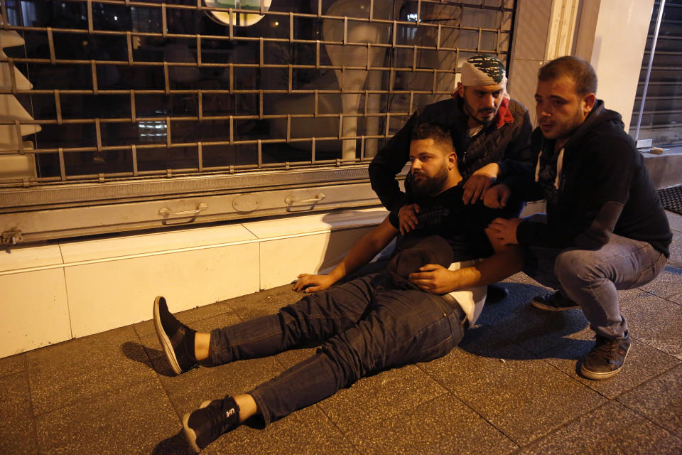 Anti-government protesters comfort their friend who fell from the tear gas, during a clash between supporters of the Shiite Hezbollah and Amal groups and the, in Beirut, Lebanon, early Monday, Nov. 25, 2019. Security forces fired tear gas amid confrontations in central Beirut that went into Monday morning between Hezbollah supporters and demonstrators protesting against Lebanon's political elite. (AP Photo/Hussein Malla)