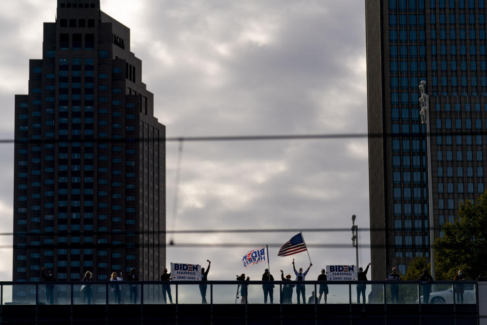 Supporters ring cow bells and wave across the train tracks during an event for Democratic presidential candidate former Vice President Joe Biden at Amtrak's Cleveland Lakefront train station, Wednesday, Sept. 30, 2020, in Cleveland, Biden is on a train tour through Ohio and Pennsylvania today. (AP Photo/Andrew Harnik)