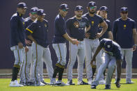 Members of the Milwaukee Brewers watch as Lorenzo Cain, bottom right, fields the ball during the team's spring training baseball workout in Phoenix, Tuesday, Feb. 23, 2021. (AP Photo/Jae C. Hong)