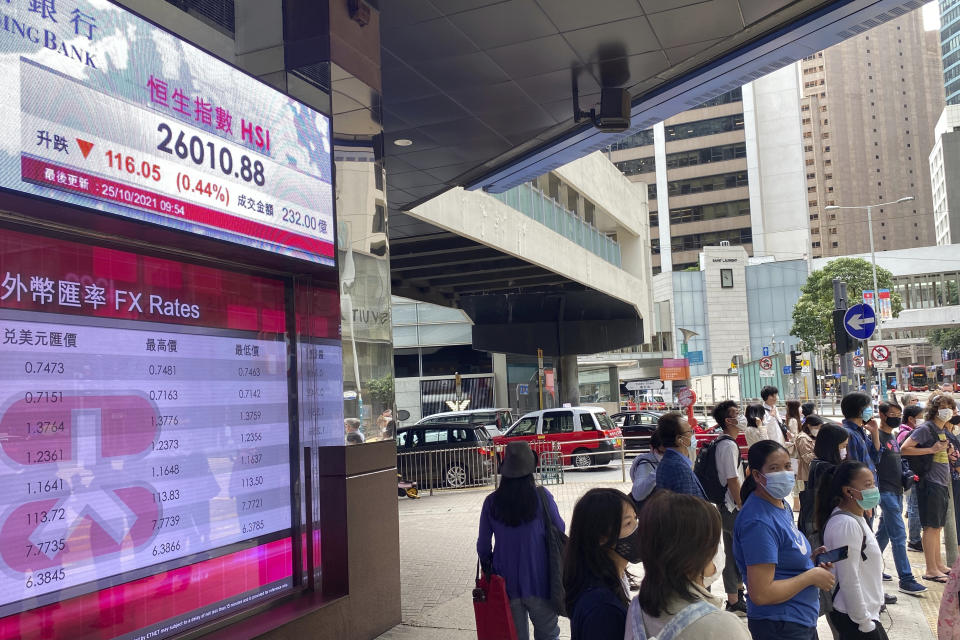 People stand in front of a bank's electronic board showing the Hong Kong share index at Hong Kong Stock Exchange in Hong Kong Monday, Oct. 25, 2021. Asian stock markets were mixed Monday after Wall Street slipped and China tightened travel controls in some areas in response to coronavirus infections. (AP Photo/Vincent Yu)