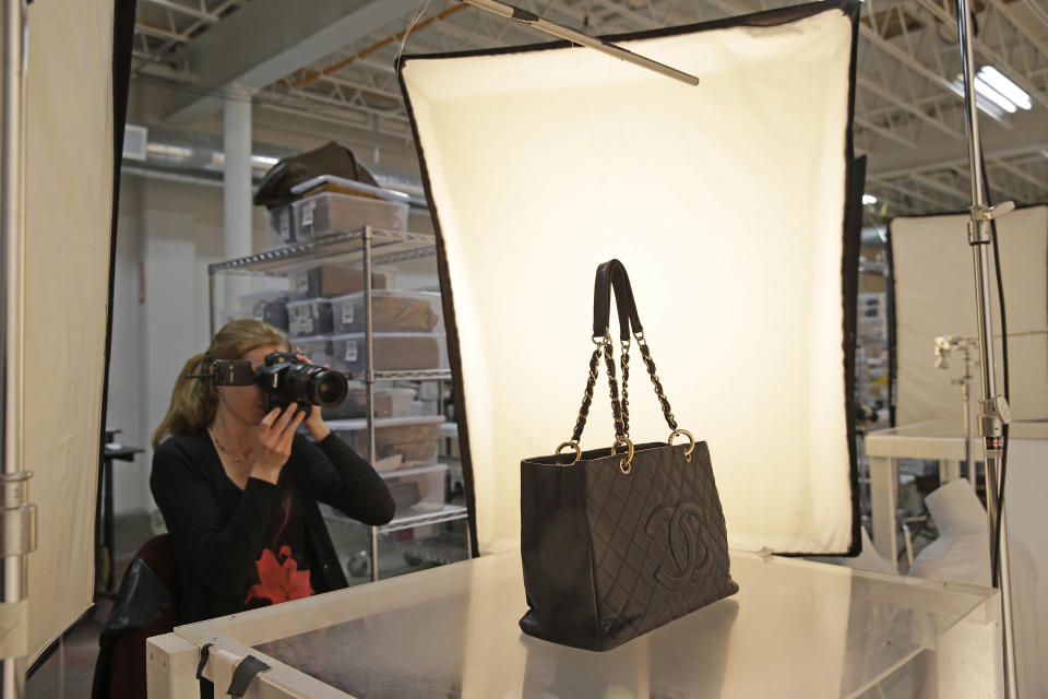 In this photo taken Wednesday, April 9, 2014, Ashley Fischer photographs a Chanel Grand Shopping Tote for an online gallery at the headquarters of The RealReal in San Francisco. An explosion of resale online sites from RealReal to Chairish that allows shoppers to easily trade in their gently used top brand handbags, furniture and gadgets for cash is changing the way Americans buy. The ease of reselling their possessions allows consumers to keep refreshing their wardrobes and homes without feeling guilty. (AP Photo/Eric Risberg)