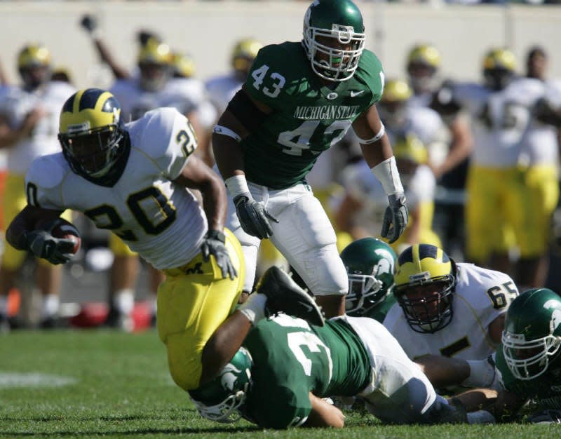 During the fourth quarter University of Michigan's Mike Hart (20) runs by Michigan State University's Kaleb Thornhill (43) and Eric Smith (36) to set up the game-tying touchdown during a rival game of  Michigan State Spartans and Michigan Wolverines at Spartan Stadium in East Lansing on Saturday, Oct. 1, 2005.