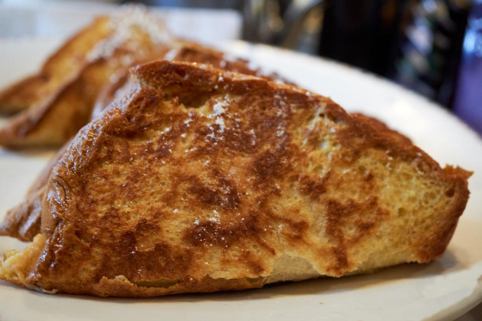 Close-up image of French toast slices dusted with powdered sugar on a white plate