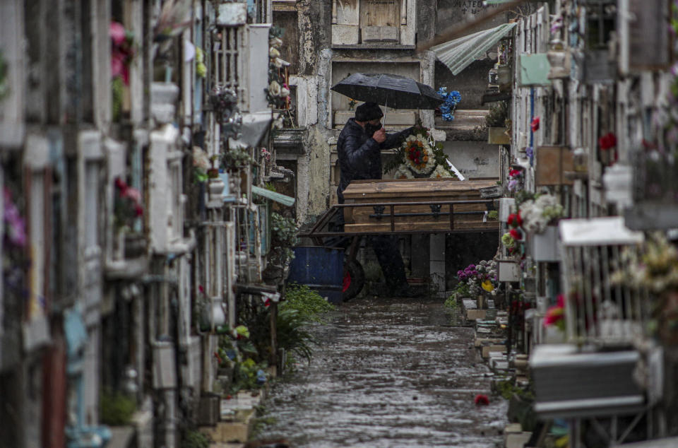 Un familiar acompaña el ataúd que contiene los restos de un ser querido que al parecer murió de complicaciones del nuevo coronavirus en el cementerio Bajos de Mena en el barrio Puente Alto a las afueras de Santiago, Chile, el sábado 4 de julio de 2020. (AP Foto/Esteban Felix)