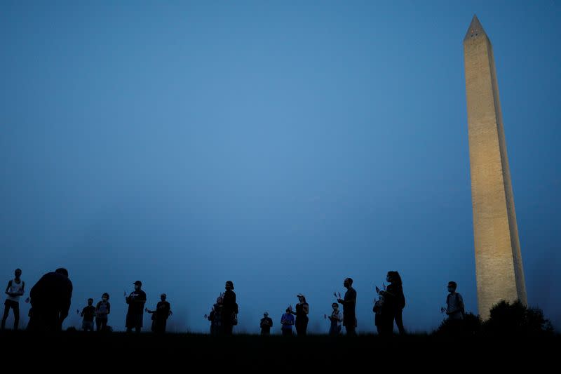 Activists stand with American flags at sunrise to memorialize victims of the coronavirus disease (COVID-19) outbreak in Washington