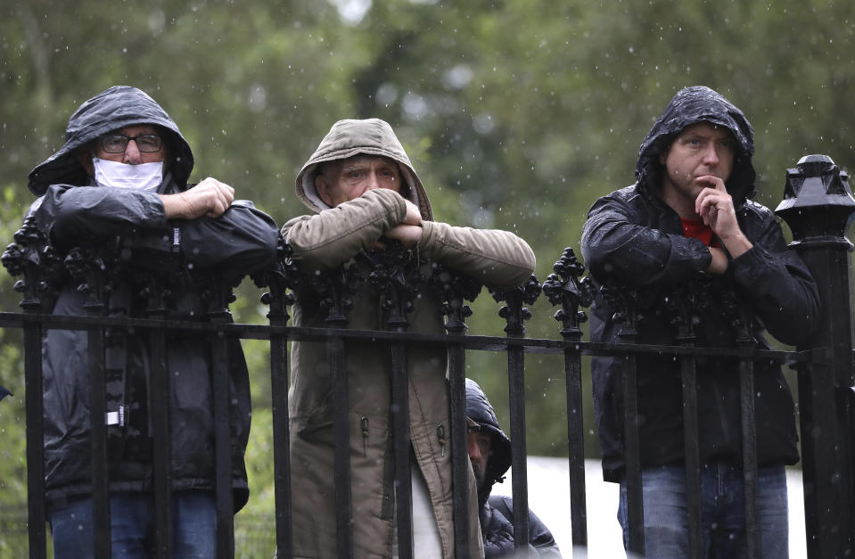 Three men watch from the railings in the rain as attendees arrive for the former Northern Ireland lawmaker and Nobel Peace Prize winner John Hume's funeral Mass at St Eugene's Cathedral in Londonderry, Northern Ireland, Wednesday, Aug. 5, 2020. Hume was co-recipient of the 1998 Nobel Peace Prize with fellow Northern Ireland lawmaker David Trimble, for his work in the Peace Process in Northern Ireland. (AP Photo/Peter Morrison)