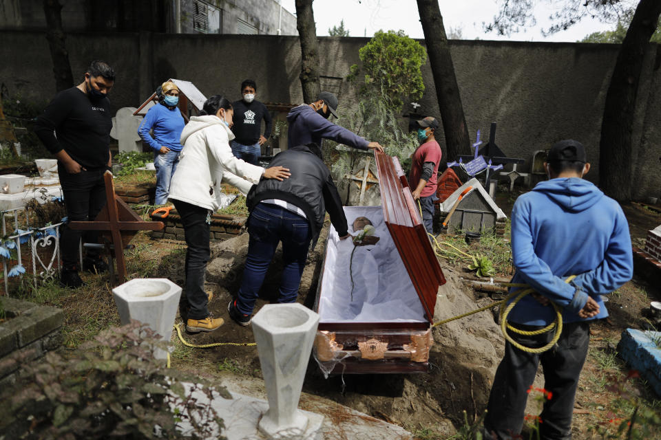 Familiares se despiden de un hombre de 63 años que murió de un ataque cardíaco, que su familia dijo que no tenía relación con el COVID-19, en el cementerio Xilotepec en Xochimilco, Ciudad de México, el lunes 27 de julio de 2020. (AP Foto/Rebecca Blackwell)