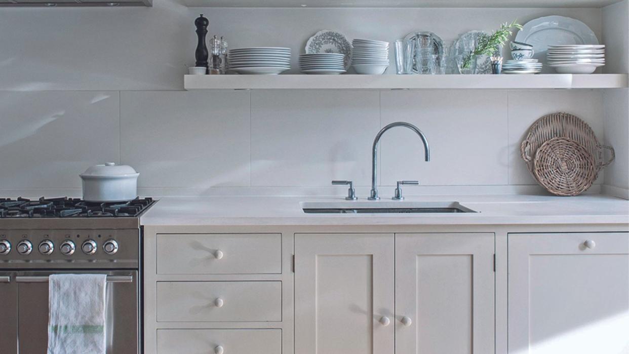  A white kitchen with four layers of open shelving displaying white kitchenware 