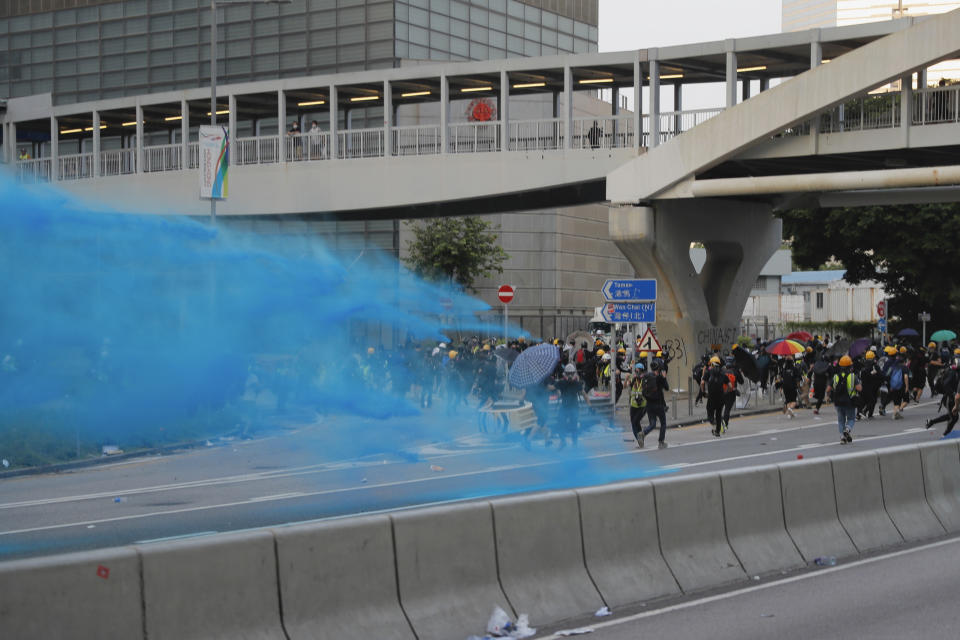 A police vehicle sprays blue-colored water towards anti-government protesters during a demonstration near Central Government Complex in Hong Kong, Sunday, Sept. 15, 2019. Police fired a water cannon and tear gas at protesters who lobbed Molotov cocktails outside the Hong Kong government office complex Sunday, as violence flared anew after thousands of pro-democracy supporters marched through downtown in defiance of a police ban. (AP Photo/Kin Cheung)