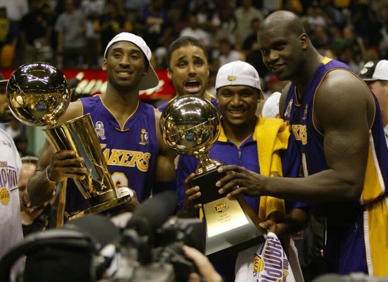 Los Angeles Lakers Kobe Bryant, left, holding the championship trophy, celebrates with teammates Rick Fox.