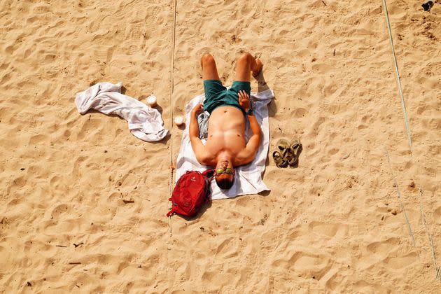 A man sunbathes on the beach in Mousehole, Cornwall, during the U.K.'s first red extreme heat warning on Monday. (Photo: Ben Birchall - PA Images via Getty Images)