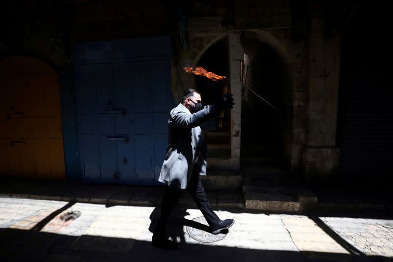 An Orthodox Christian worshipper holds candles-stick with fire following The Holy Fire ceremony that took place in the Church of the Holy Sepulchre in Jerusalem's Old City amid the coronavirus disease (COVID-19) outbreak