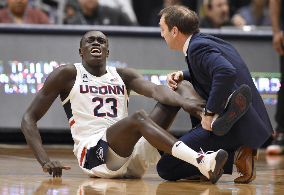 Connecticut's Akok Akok (23) reacts while tended to by head trainer James Doran in the first half of an NCAA college basketball game against Memphis, Sunday, Feb. 16, 2020, in Hartford, Conn. (AP Photo/Jessica Hill)