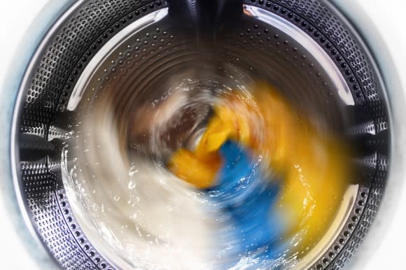 Washing machine in midcycle, with clothes being spun around in water